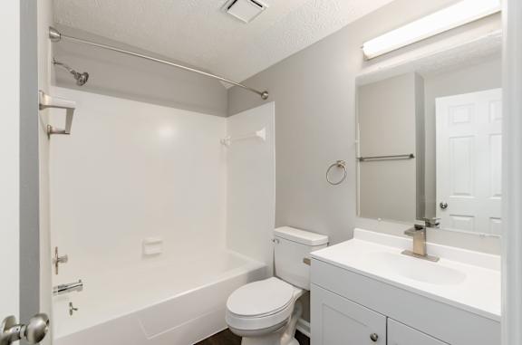 A white bathroom with a toilet, sink, and bathtub.