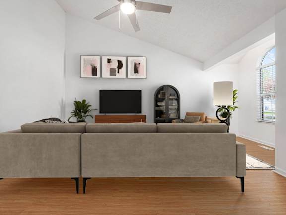 A living room with a grey couch and a television on a wooden stand.