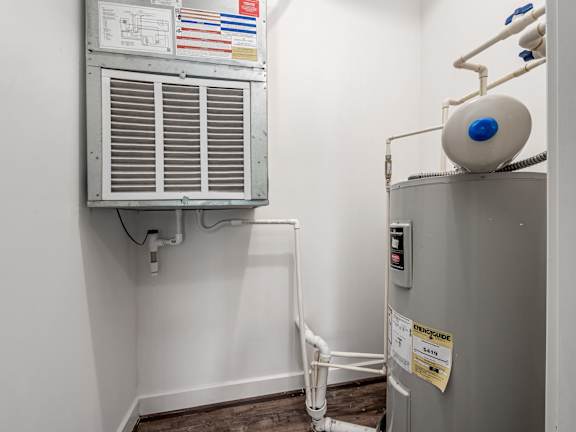 A room with a wall-mounted air conditioning unit and a tank on top of a cabinet. at River View at Bexley Apartments, River View at Bexley, Ohio