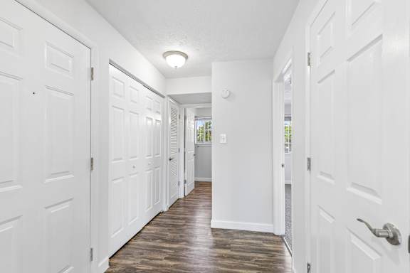 A long hallway with white doors and wood floors.