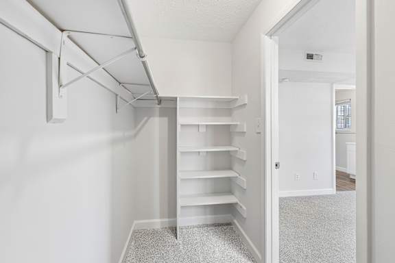 A white room with a long shelf and a doorway leading to another room.