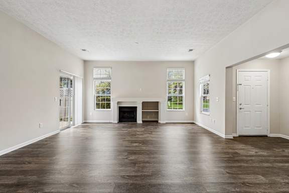 A large empty room with a fireplace and wooden floors.