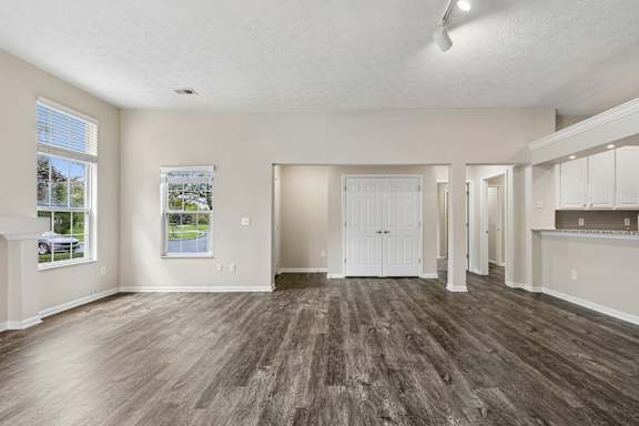 A spacious room with wood flooring and white walls.