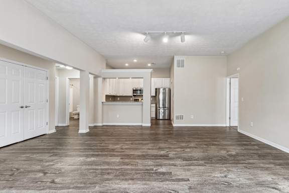 A spacious living room with a kitchen in the background.