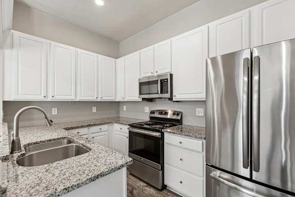 A kitchen with white cabinets and a granite countertop.