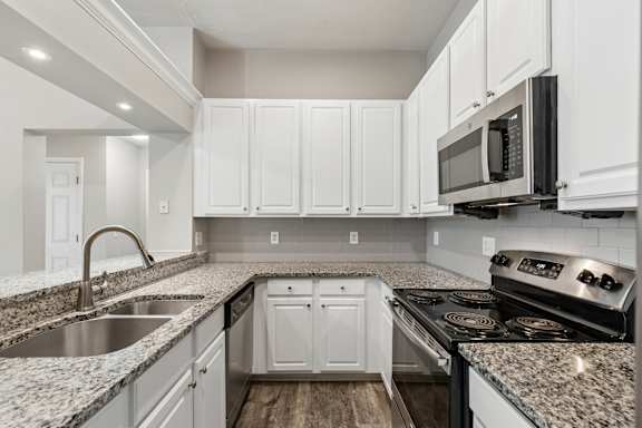 A kitchen with white cabinets and a black microwave.