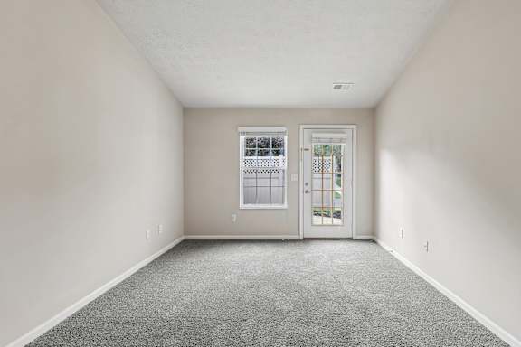 A room with a carpeted floor and a door leading to another room.