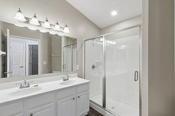 A bathroom with a white sink and a white shower.
