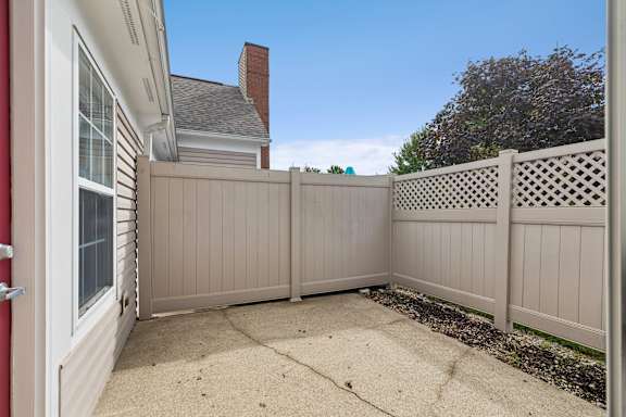 A white house with a red door and a tan fence.