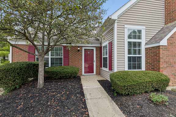 A house with a red door and a tree in front.