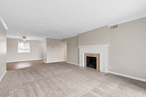 A spacious living room with a fireplace and carpeted floor.