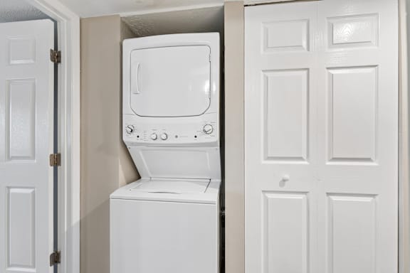A white washing machine is in a small space between two doors.