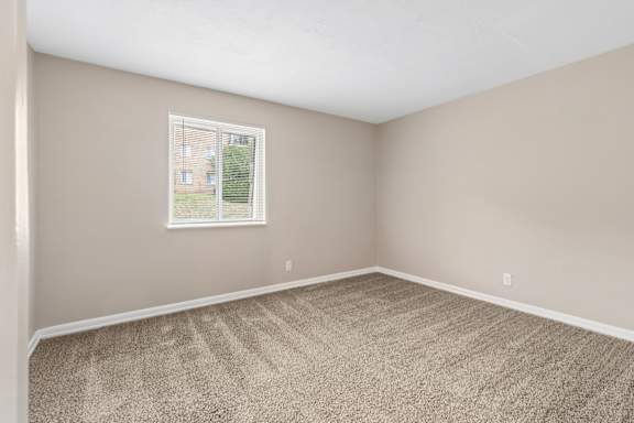 A room with a carpeted floor and a window.