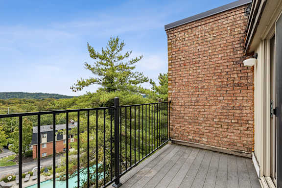 A balcony with a black railing and a brick wall.
