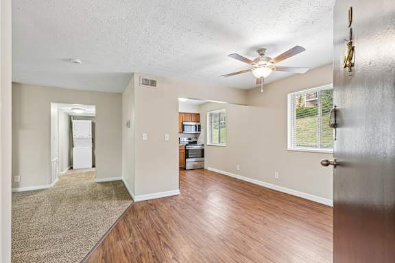 A room with a ceiling fan and a brown rug on the floor.