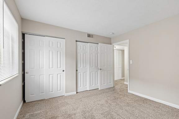 A room with white doors and carpeted floor.