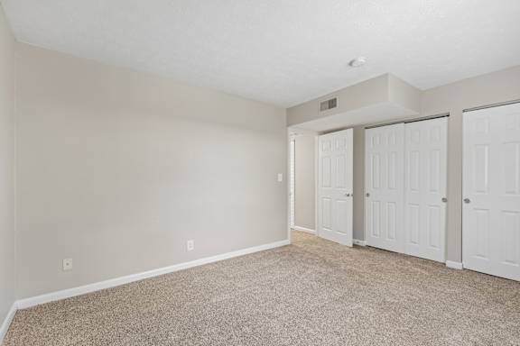 A room with white doors and carpeted floor.