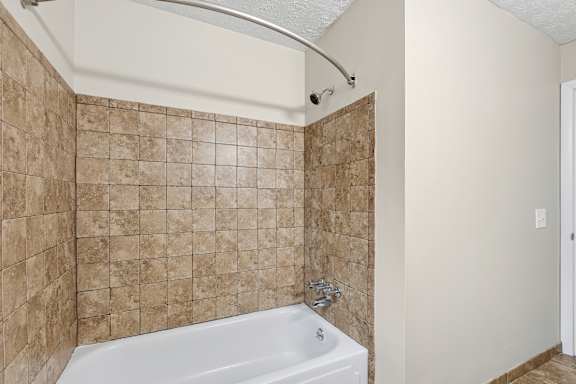 A bathroom with a tiled shower and a white bathtub.
