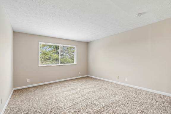 A room with a window and carpeted floor.