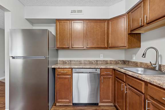 A kitchen with wooden cabinets and a stainless steel refrigerator.