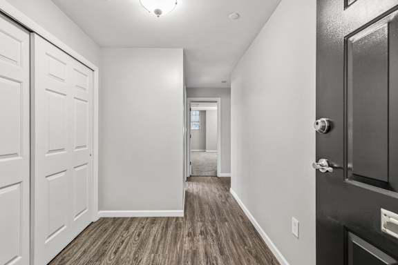 A hallway with white walls and wood flooring.