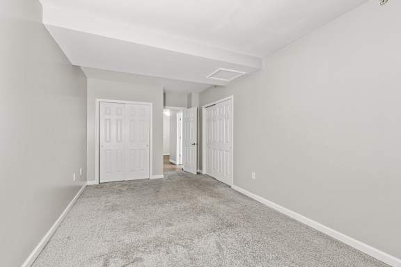 A room with white doors and carpeted floor.