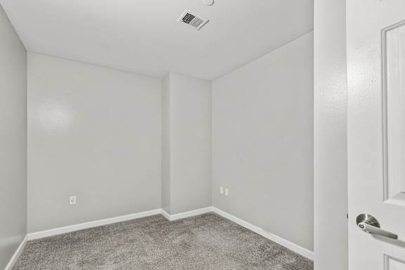 A room with a carpeted floor and a white door.