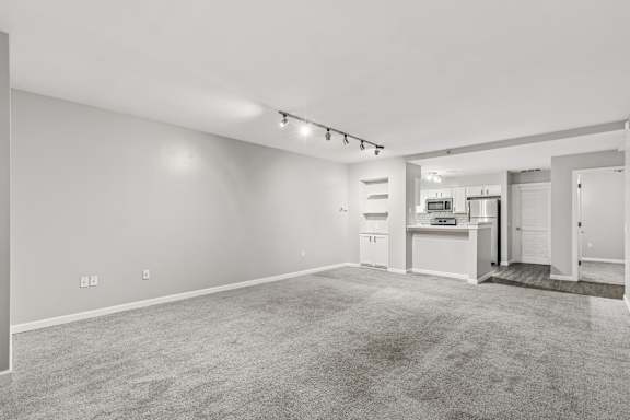 A spacious living room with a kitchen area in the background.
