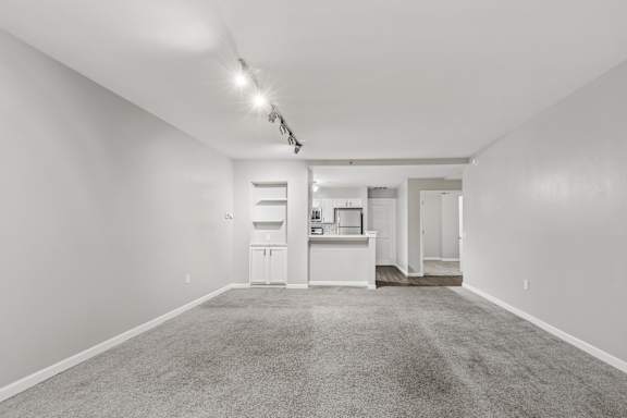 A spacious, empty room with a kitchenette in the background.