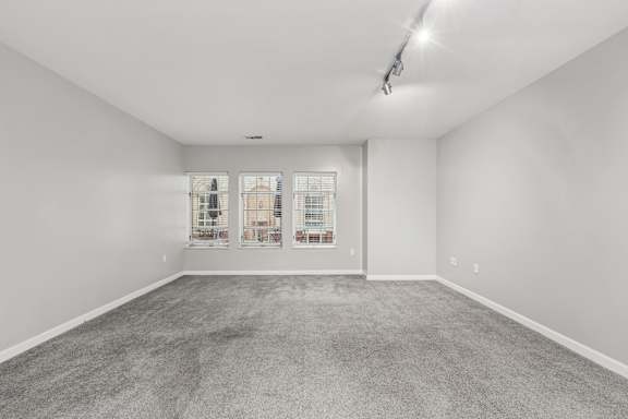 A spacious room with a grey carpet and white walls.