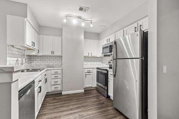 A modern kitchen with stainless steel appliances and white cabinetry.