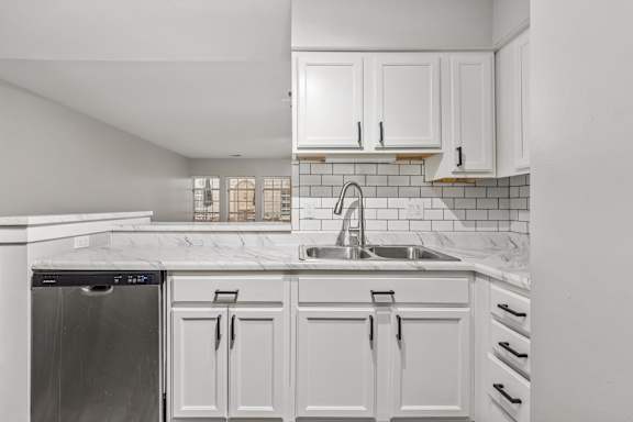 A kitchen with white cabinets and a stainless steel dishwasher.