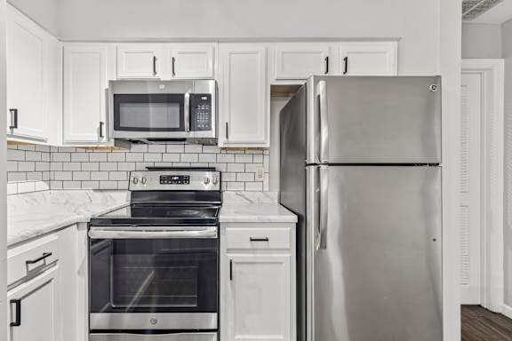 A kitchen with a stainless steel refrigerator and a black stove top oven.