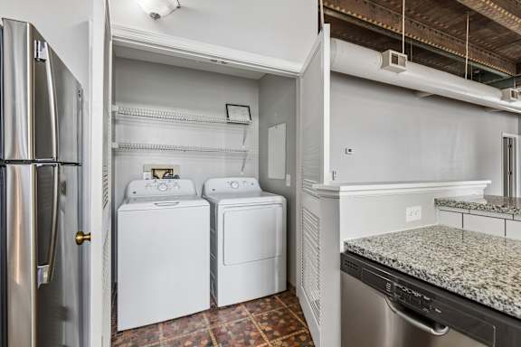A laundry room with a washer and dryer and a refrigerator.