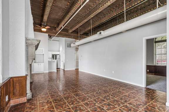 A large empty room with a tiled floor and exposed ceiling beams.