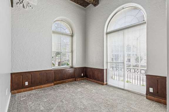 A room with two arched windows and a balcony with a railing.