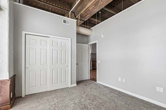 A room with a white door and a grey carpet.