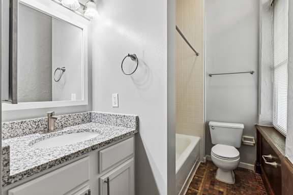 A bathroom with a marble counter top and a toilet.