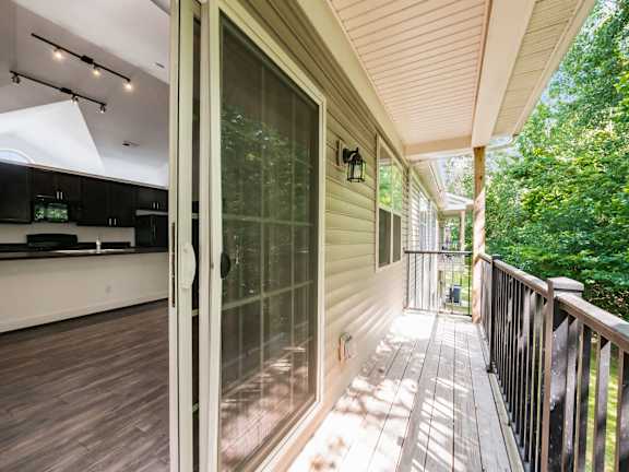 A glass door leads to a deck with a black railing. at River View at Bexley Apartments, River View at Bexley, OH, 43209