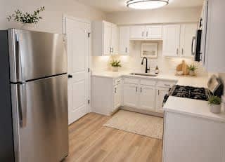 A kitchen with white cabinets and a stainless steel refrigerator.