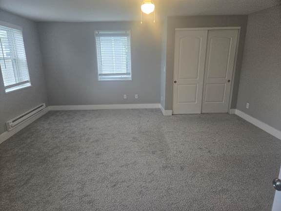 A room with a carpeted floor, a door, and a window with blinds.