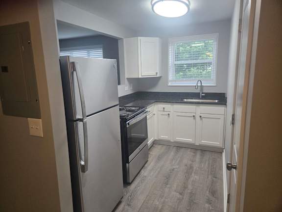A kitchen with a refrigerator, oven, and sink.
