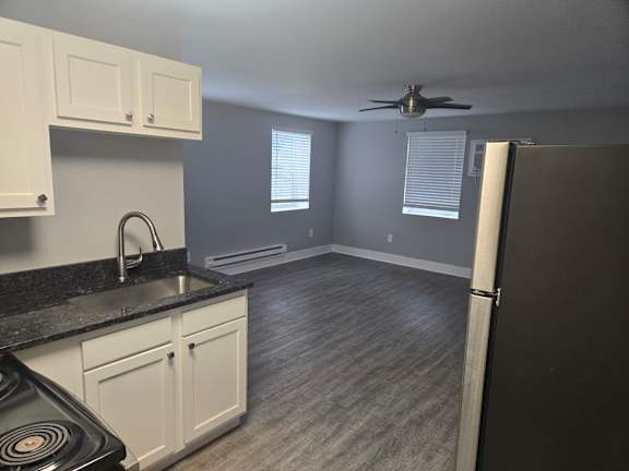 A kitchen with a black countertop and white cabinets.