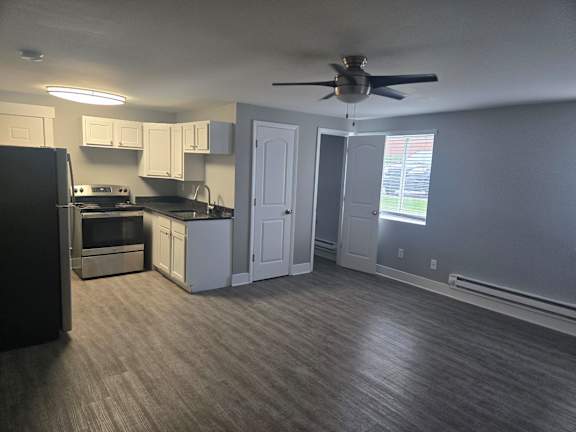 A kitchen with a black refrigerator and a fan on the ceiling.