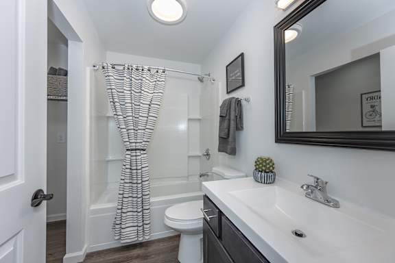 A bathroom with a white toilet, a white sink, and a white shower curtain. at Ten31, Dayton, Ohio
