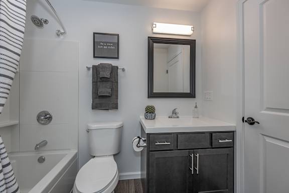 A white toilet sits next to a bathtub in a bathroom. at Ten31, Dayton, OH
