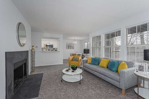 A living room with a grey couch and a fireplace at Indian Lookout Apartments, West Carrollton, OH, 45449