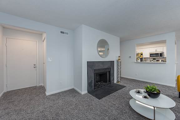 A living room with a grey carpet and a fireplace at Indian Lookout Apartments, West Carrollton, Ohio