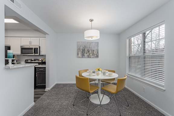 A dining area with a table and chairs is shown at Indian Lookout Apartments, West Carrollton