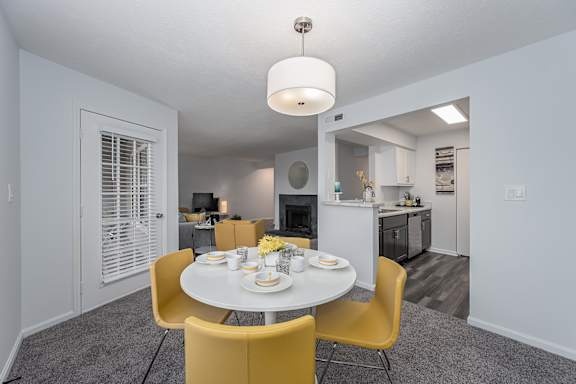 A dining room with a table set for two with yellow chairs at Indian Lookout Apartments, West Carrollton
